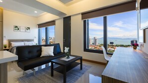 A modern living room with a sofa, coffee table, and a view of the city and sea. - Tropicana 218 Macalister (George Town)