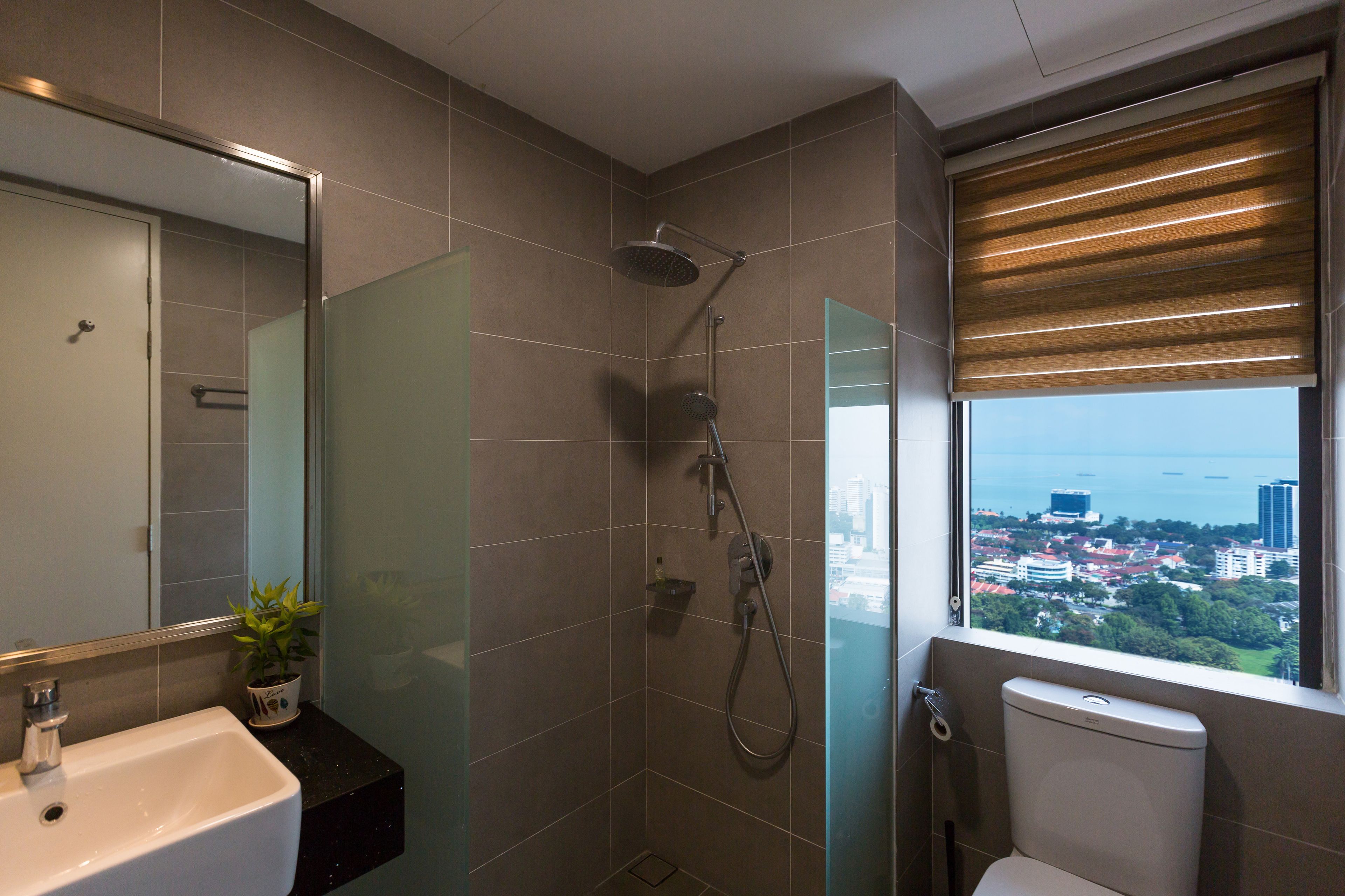Et moderne badeværelse med brusebad bag glas, toilet og håndvask.