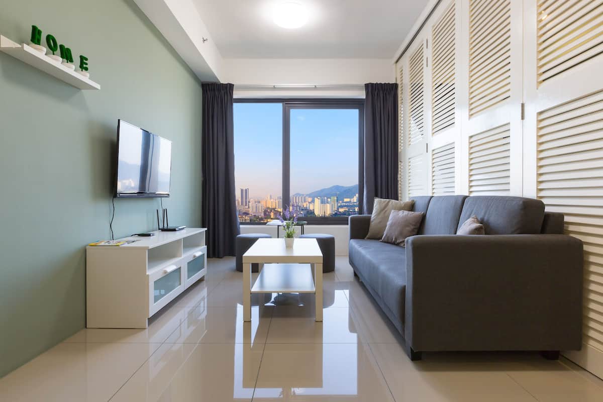 A modern living room with a sofa, a coffee table, a TV, and a city view through large windows.
