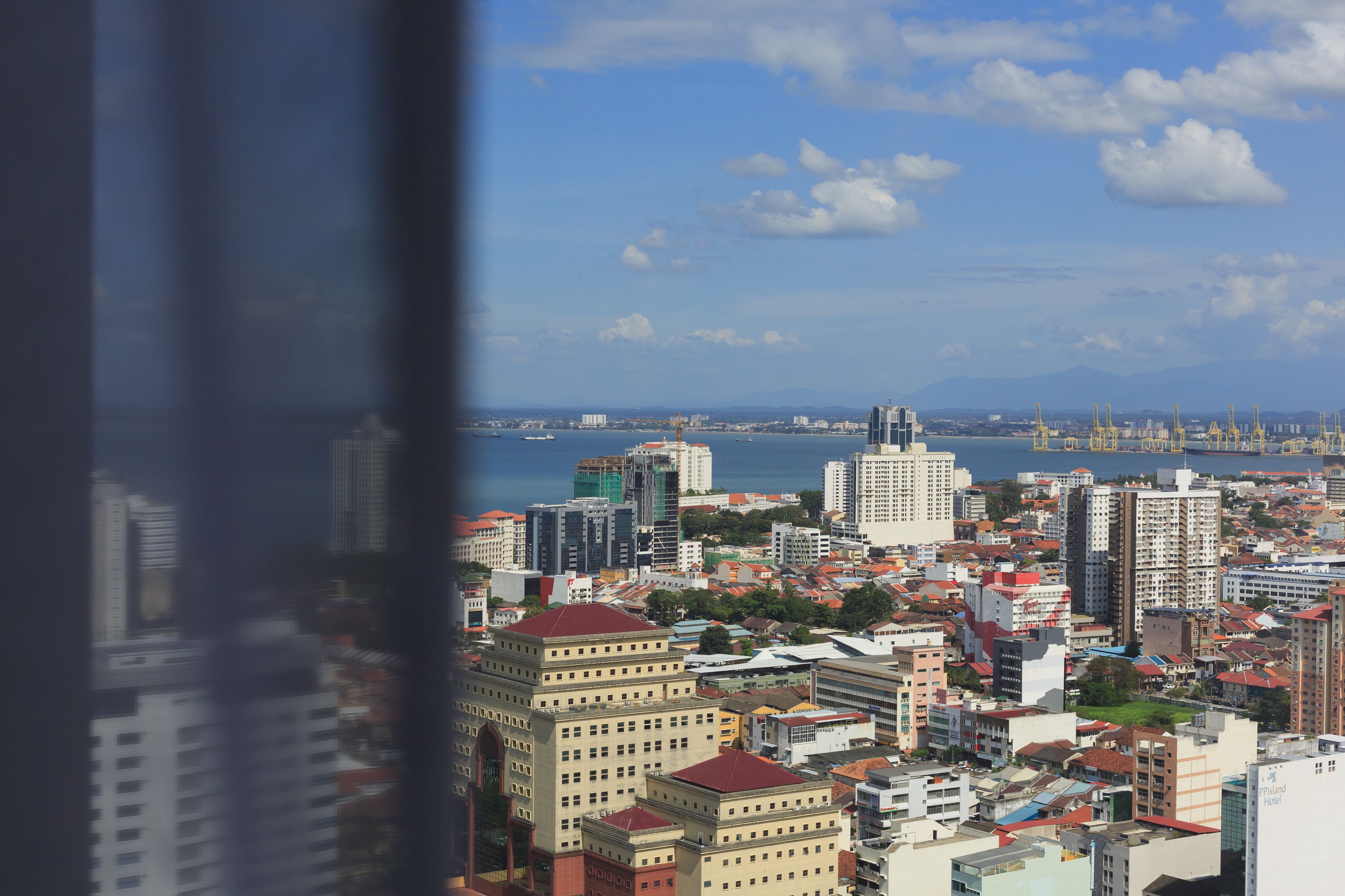 A cityscape with high-rise buildings, a body of water, and a distant mountain range.