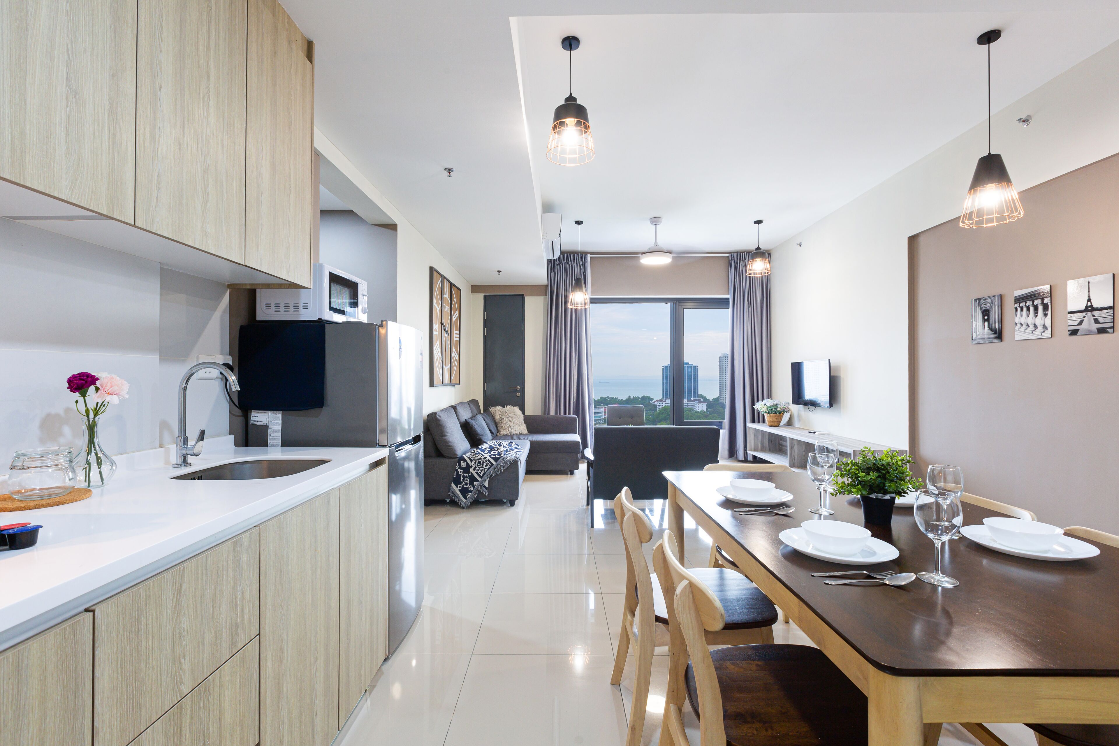 Una cocina moderna con comedor, armarios de madera e iluminación colgante.