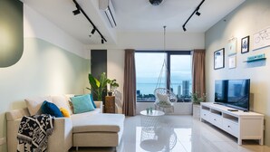 A modern living room with a sofa, TV stand, and a view of the city. - Tropicana 218 Macalister (George Town)