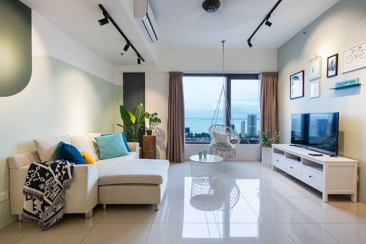 A modern living room with a sofa, TV stand, and a view of the city.