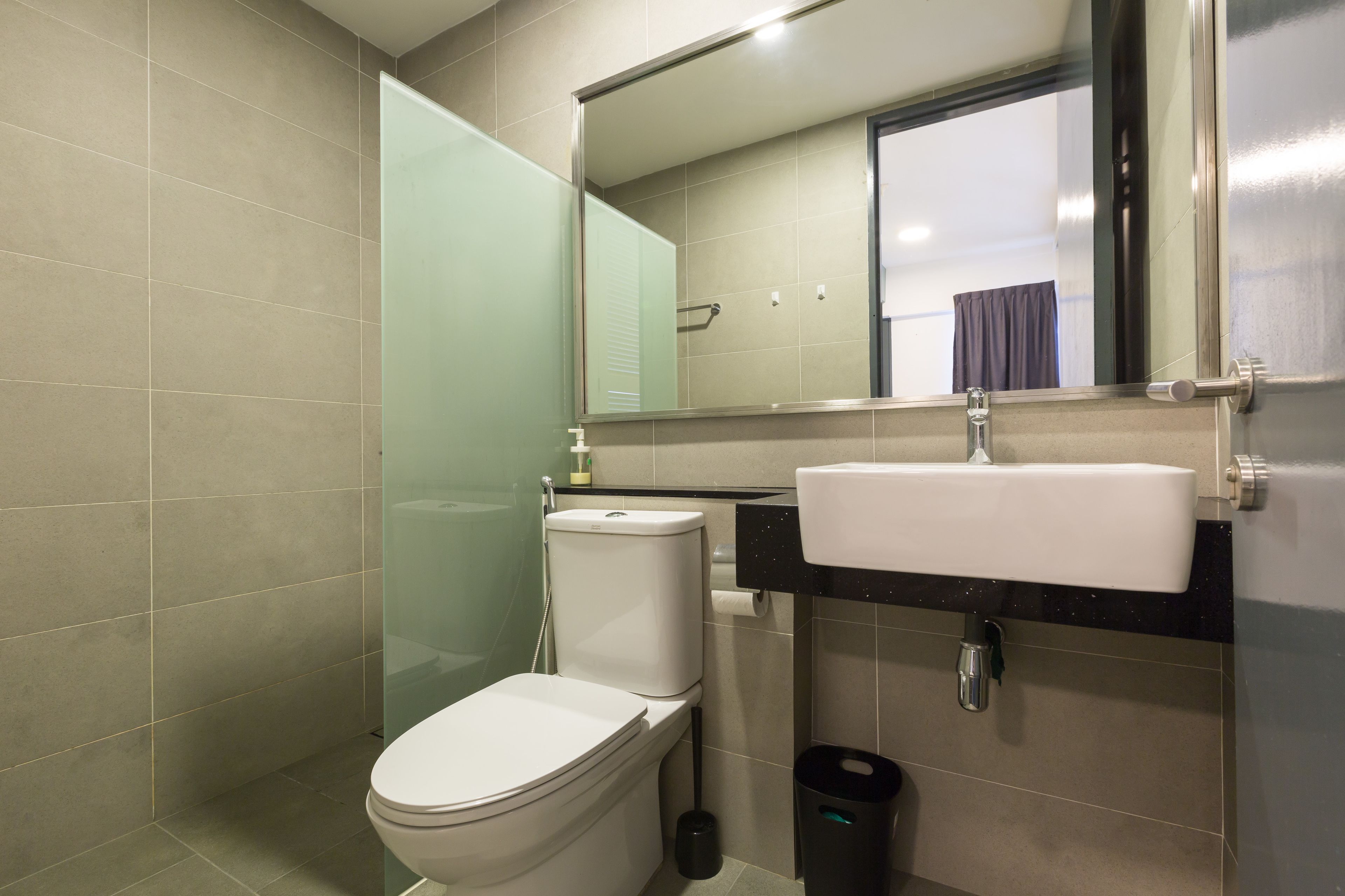 A modern bathroom with a toilet, sink, and mirror.