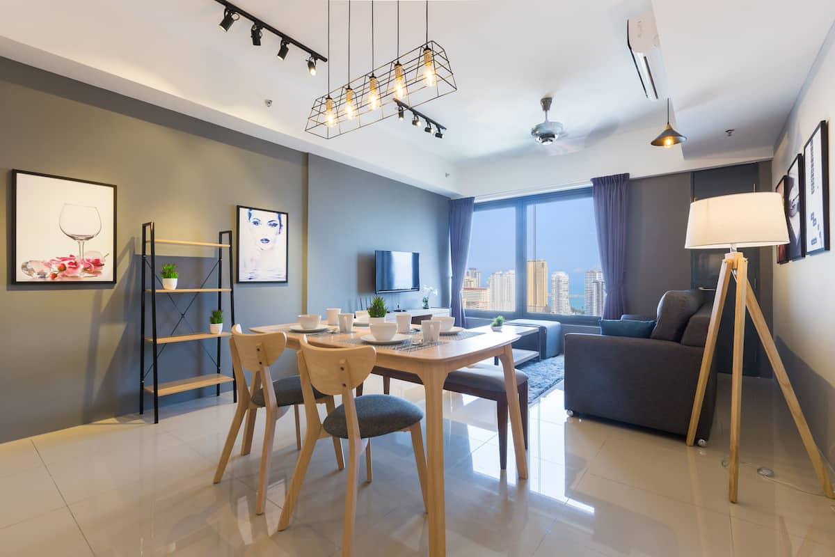 A modern living room with a dining area, a sofa, a TV, and a city view.