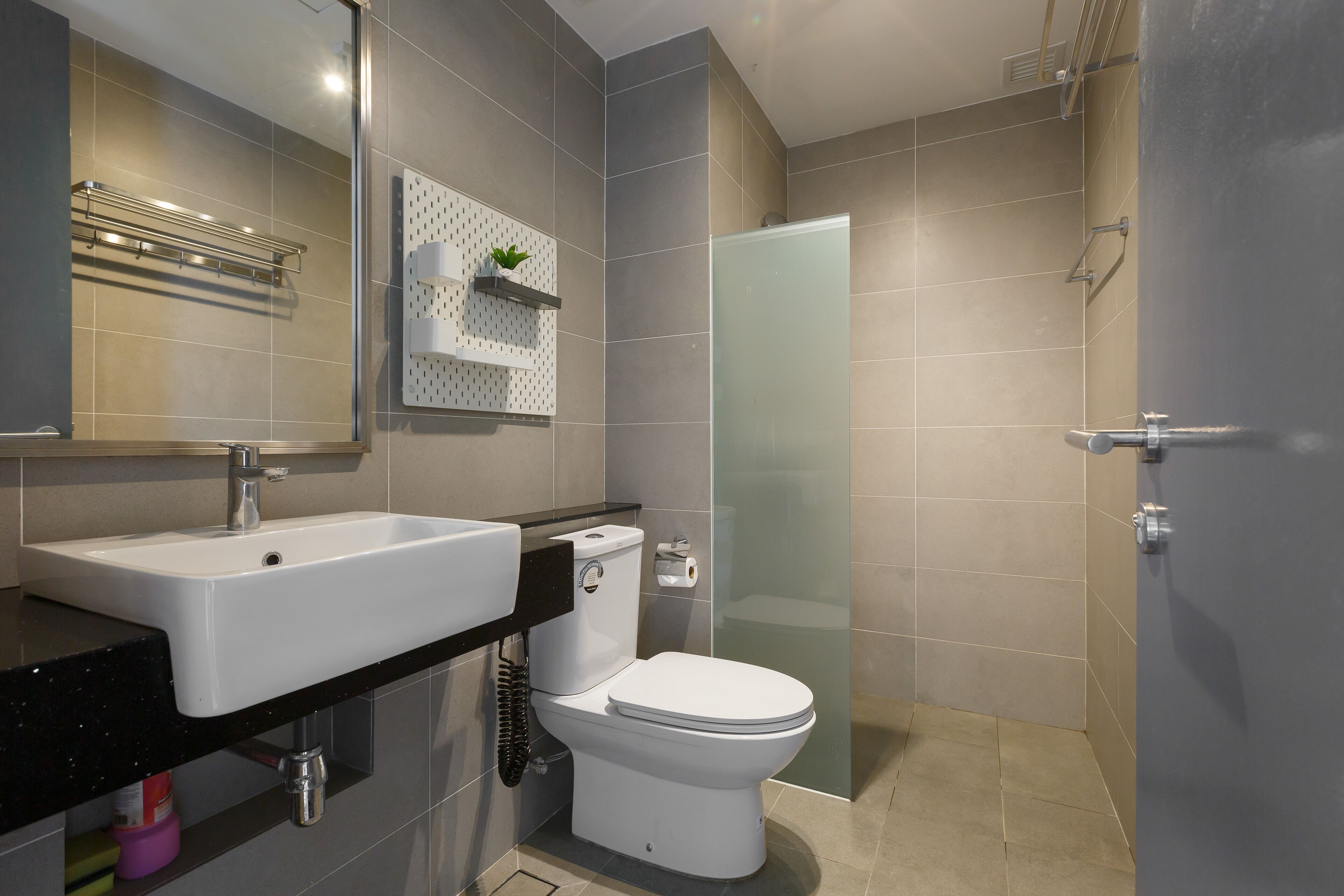 A modern bathroom with a white sink, toilet, and glass shower enclosure.