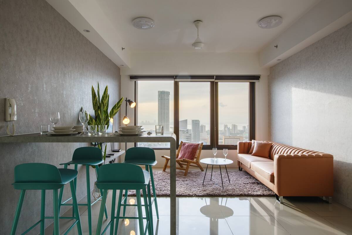 A modern living room with a sofa, chairs, a coffee table, and a dining area with a bar.