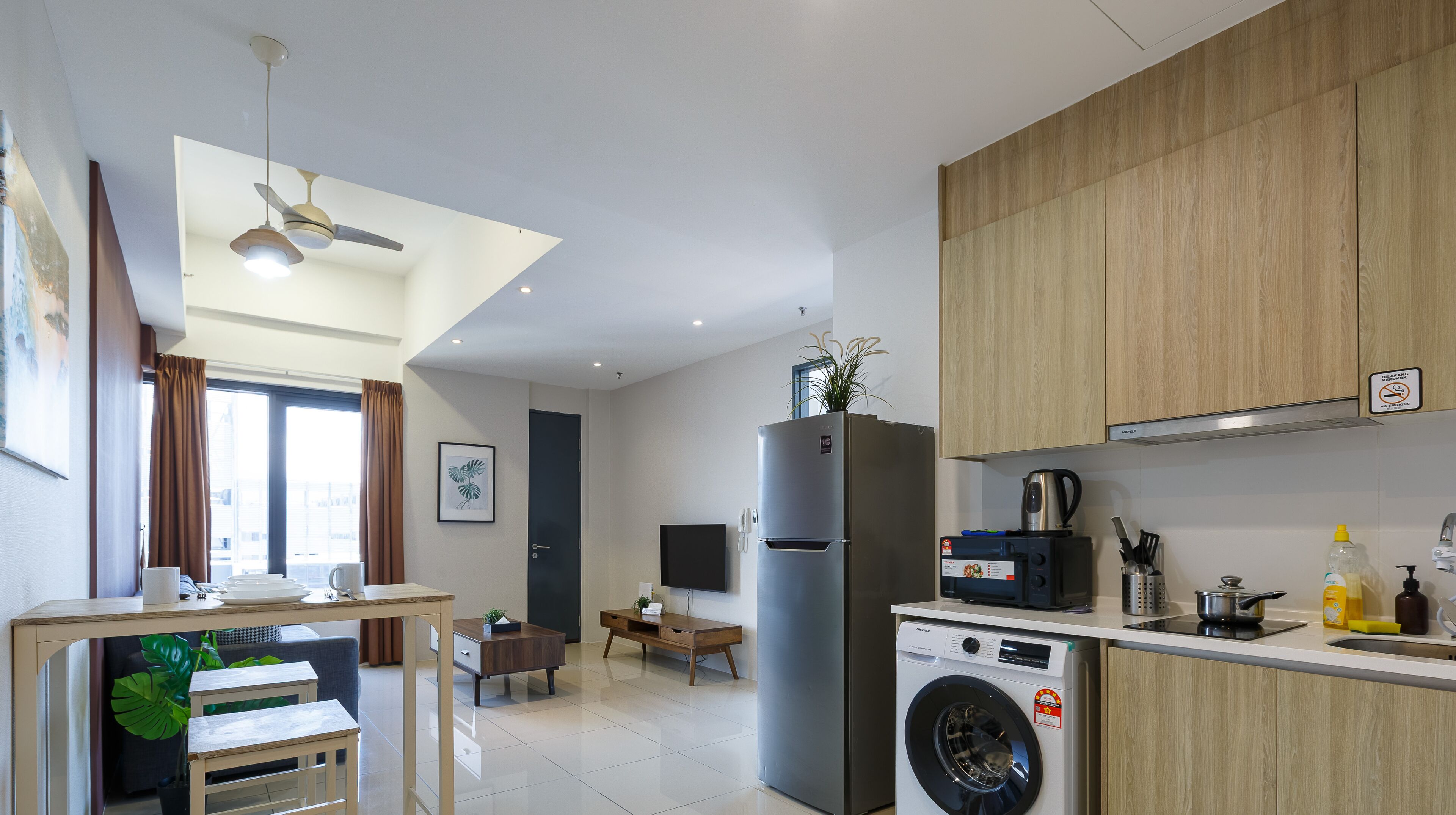 A modern kitchen with a built-in washing machine, a refrigerator, and wooden cabinets.
