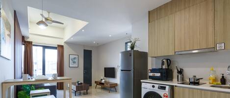 A modern kitchen with a built-in washing machine, a refrigerator, and wooden cabinets.