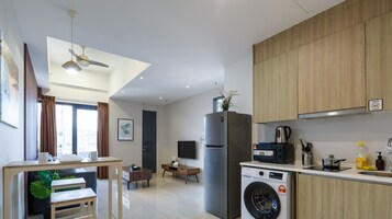 A modern kitchen with a built-in washing machine, a refrigerator, and wooden cabinets.