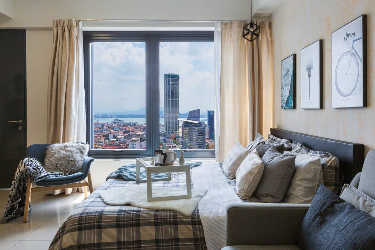 A modern bedroom with a large window, a bed, a sofa, and a chair.