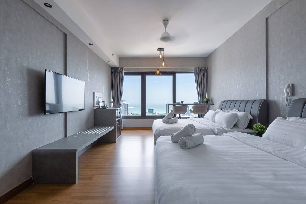 A modern hotel room with a large bed, a desk, a flat-screen TV, and a view of the city.