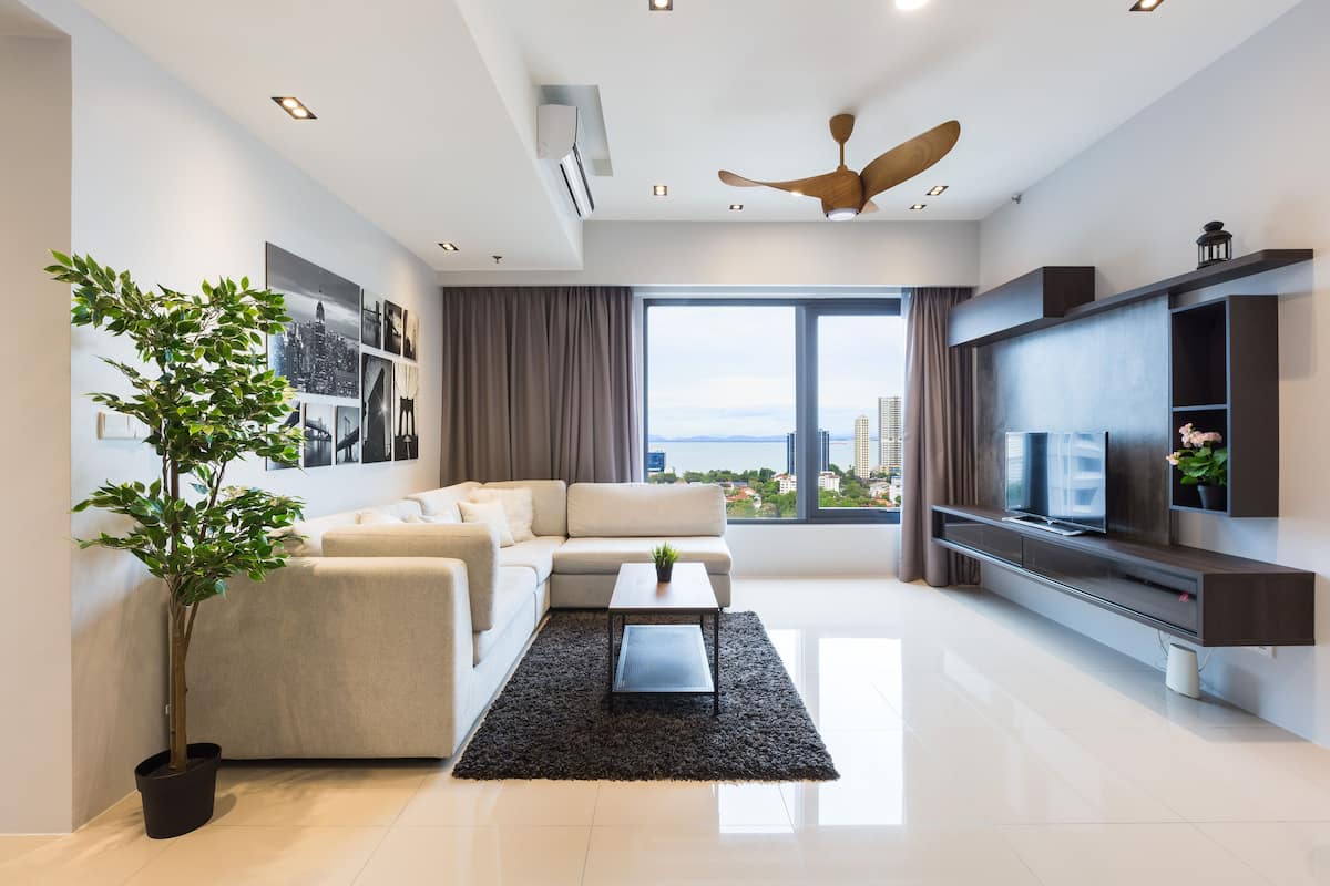 A modern living room with a sofa, a coffee table, a TV, and a large window with a city view.