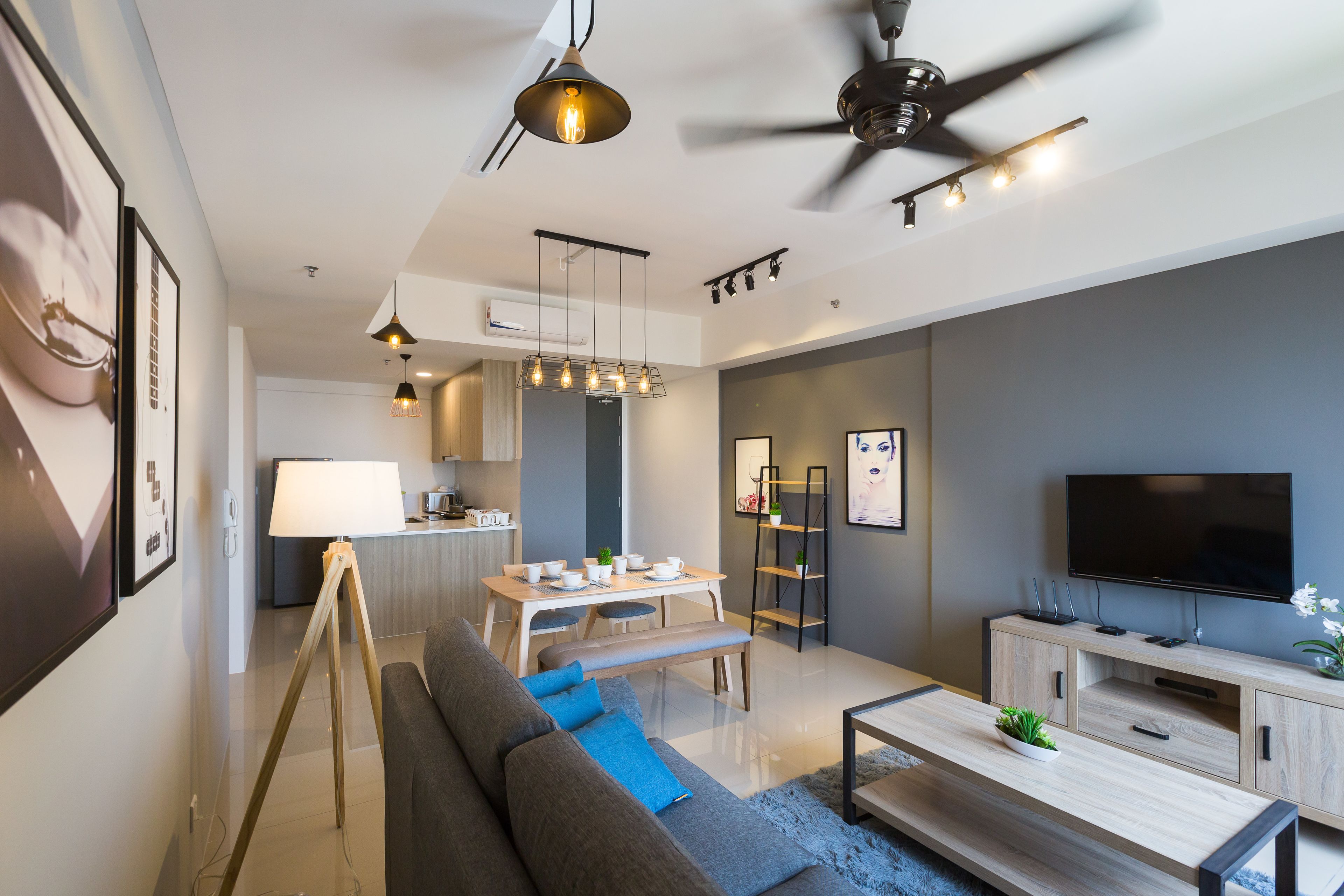 A modern living room with a sofa, coffee table, TV, and dining area.