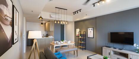 A modern living room with a sofa, coffee table, TV, and dining area.
