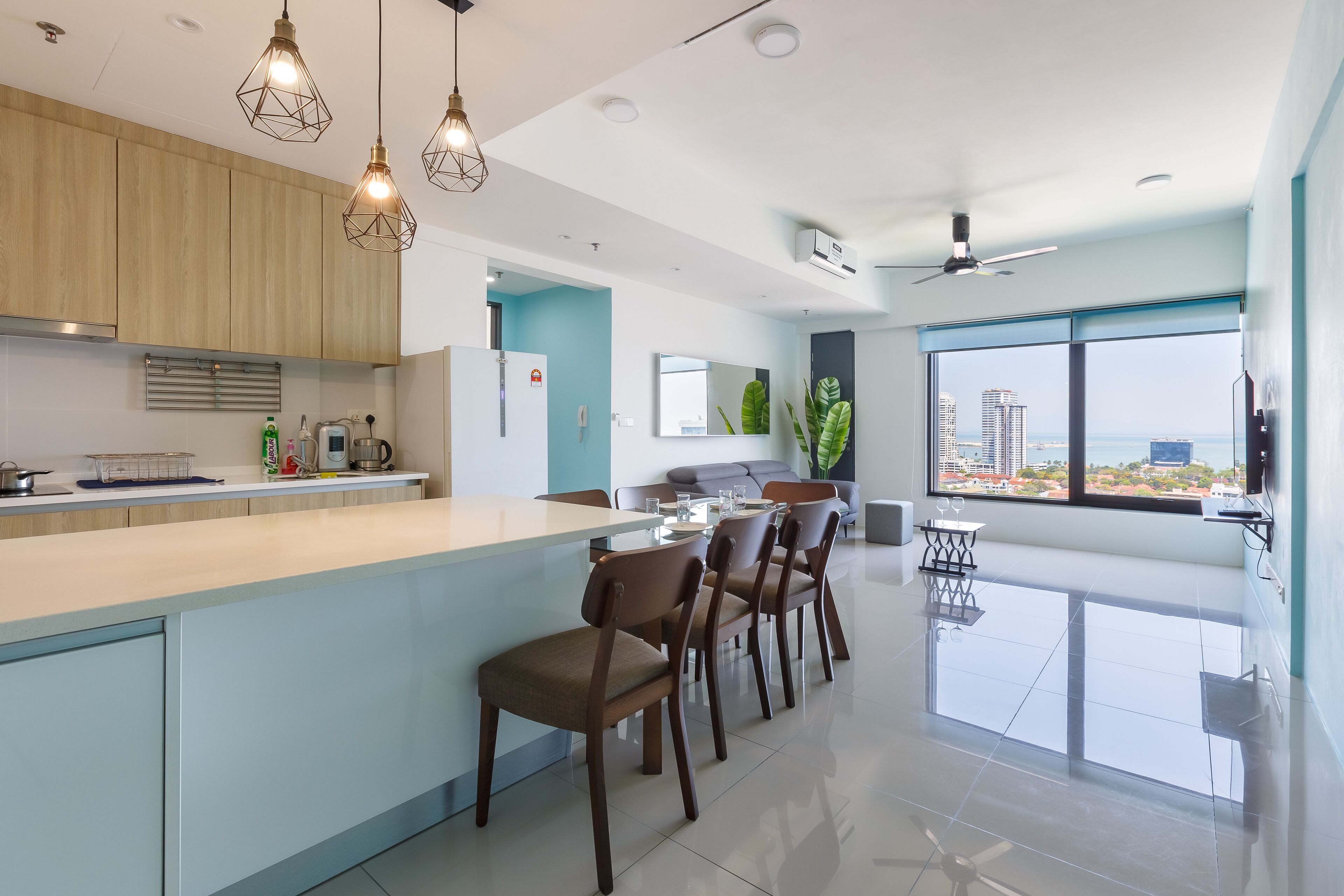 A modern kitchen with a central island, wooden cabinets, and pendant lighting.