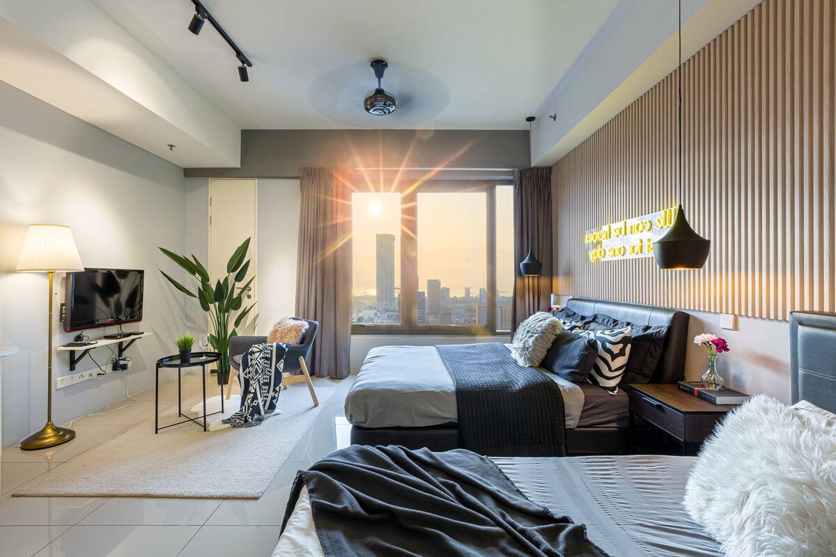 A modern hotel room with a large bed, a TV, a desk, and a city view.