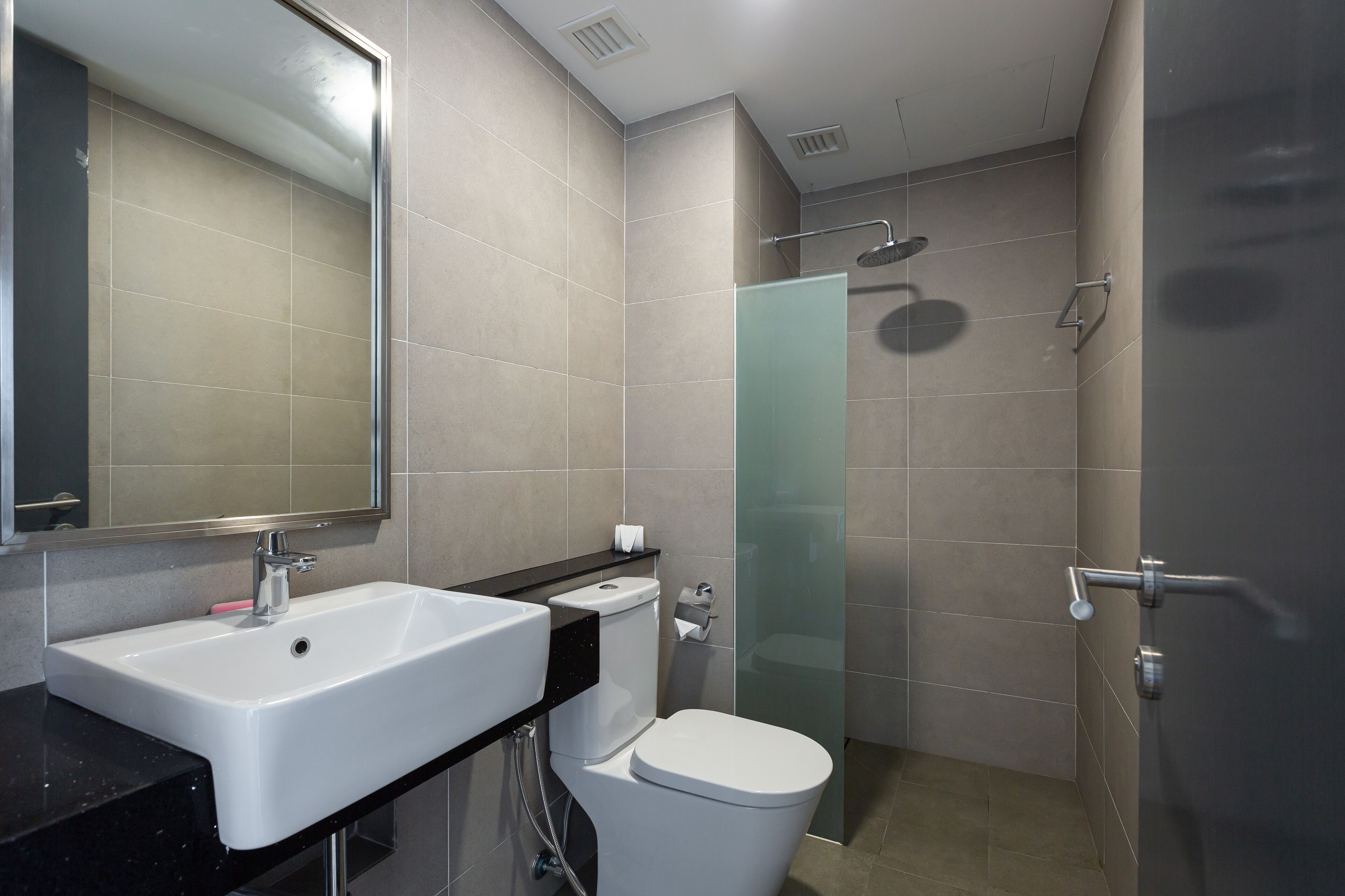 Une salle de bain moderne avec un lavabo blanc, un miroir, des toilettes et une douche à parois de verre.