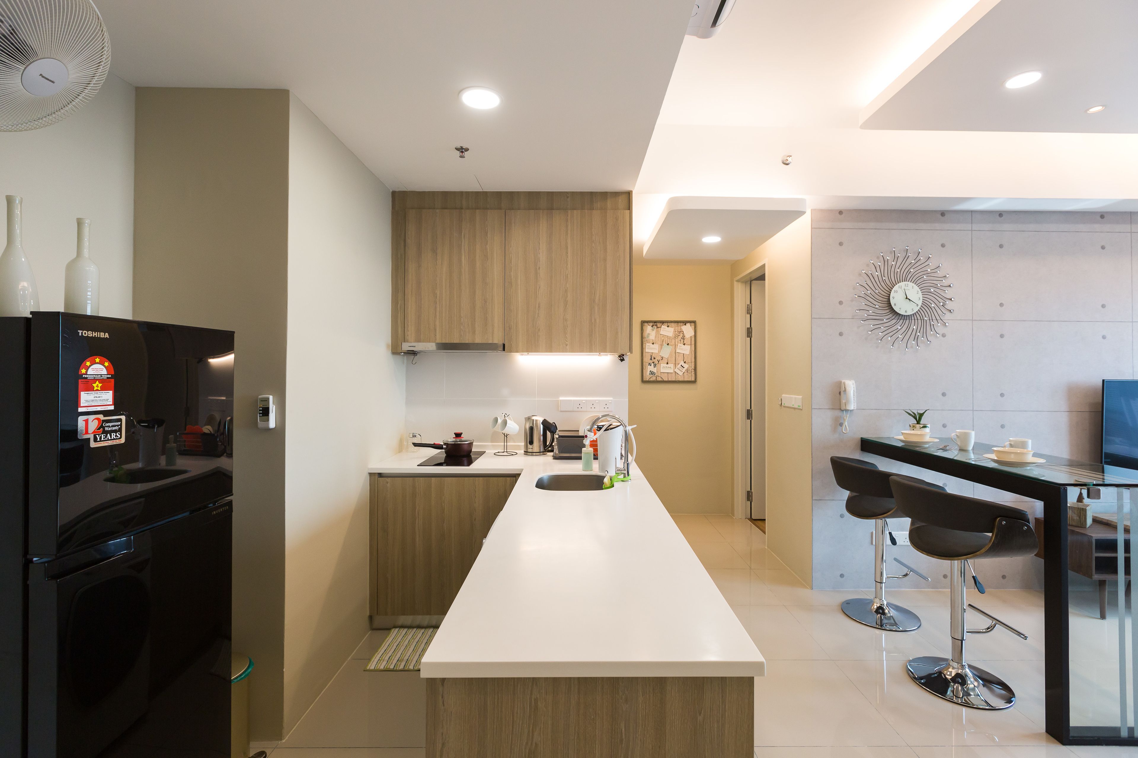 A modern kitchen with a central island, black appliances, and a bar area with stools.