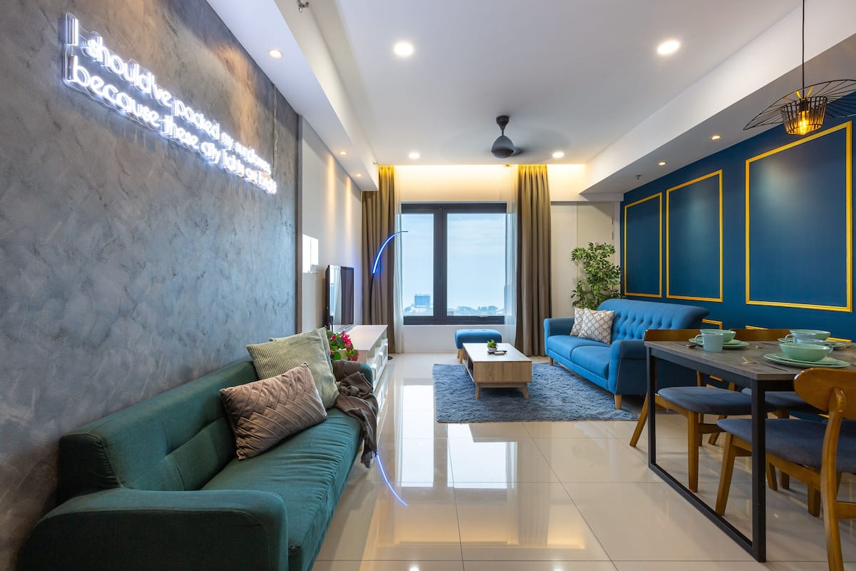 A modern living room with a sofa, a dining table, and a blue accent wall.