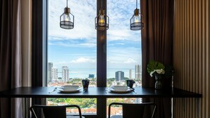 A dining table with two chairs, a vase with flowers, and a view of a cityscape through a window. - Tropicana 218 Macalister (George Town)