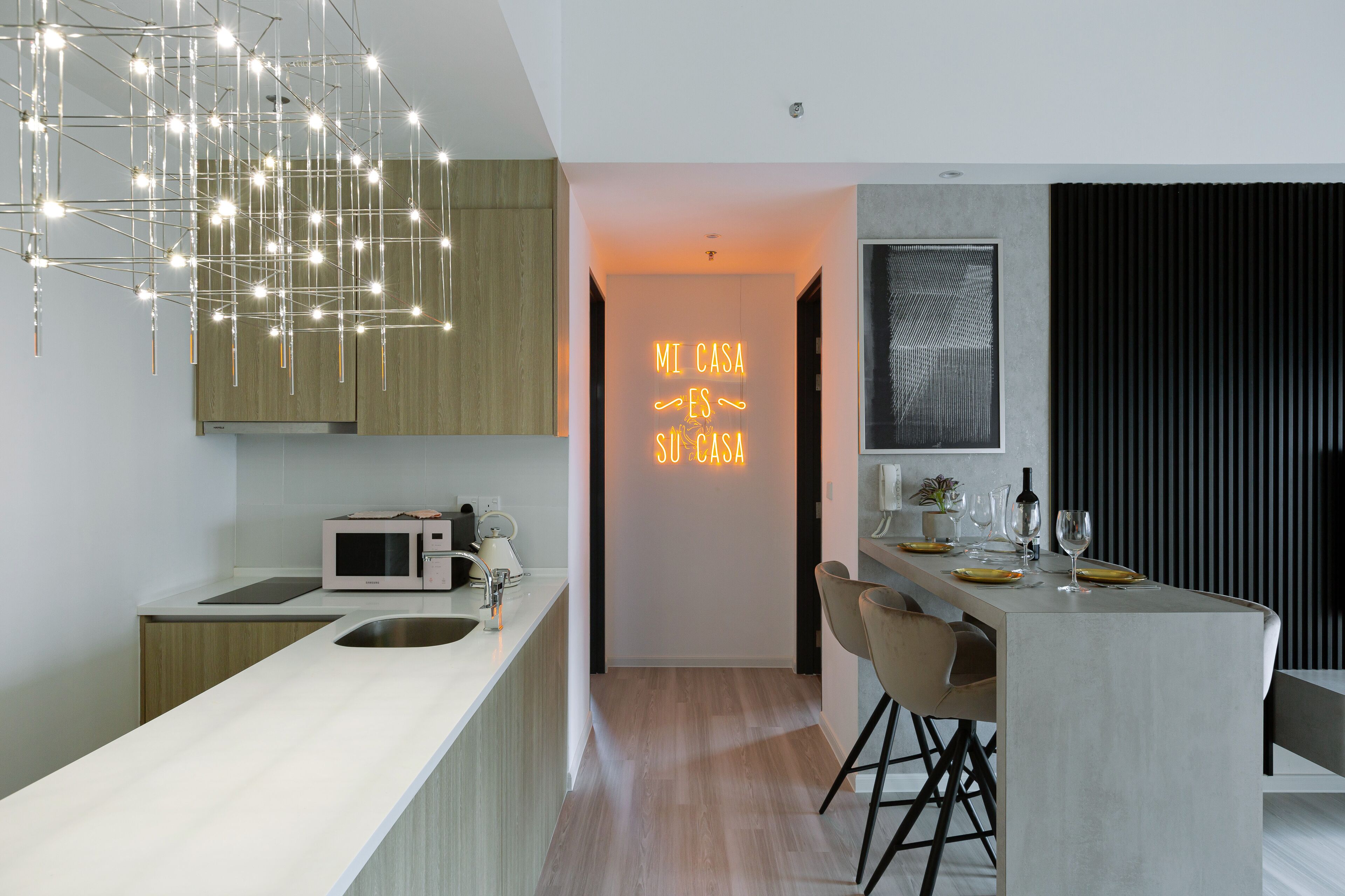 A modern kitchen with a central island, a microwave, and a neon sign.