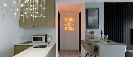 A modern kitchen with a central island, a microwave, and a neon sign.
