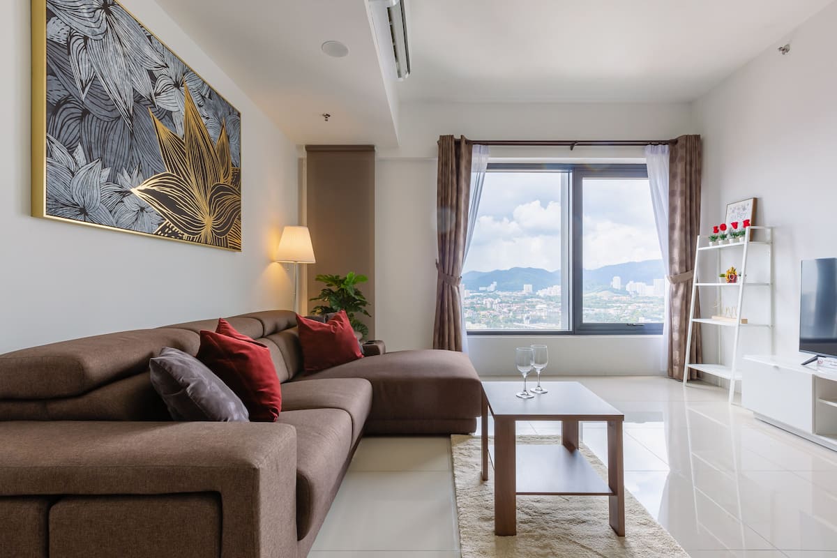 A modern living room with a sectional sofa, a coffee table, and a large window offering a city view.