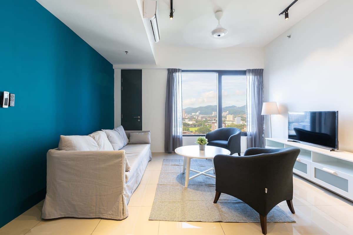 A modern living room with a sofa, armchairs, a coffee table, and a TV.