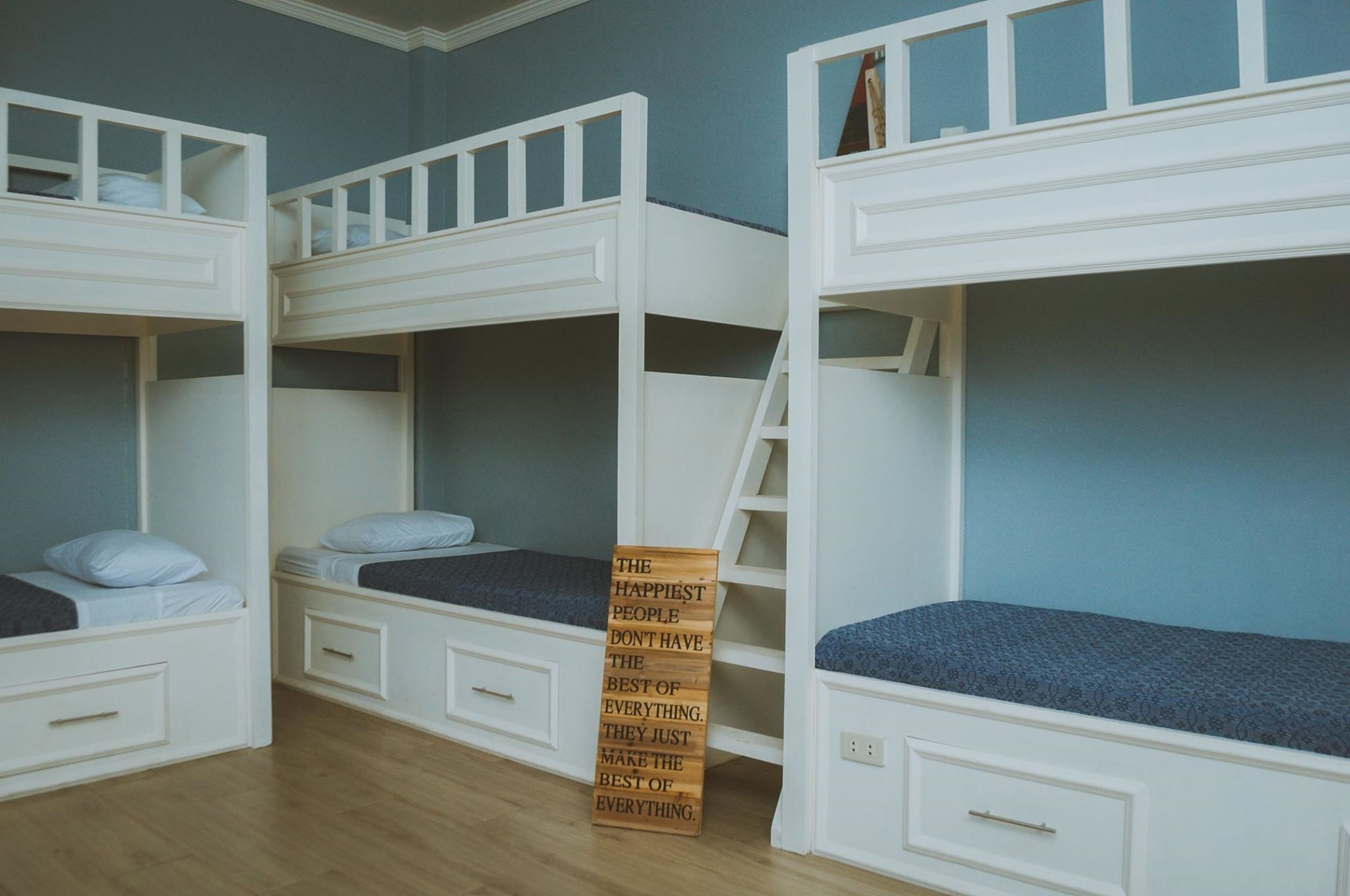 A bunk bed room with a ladder and a motivational quote sign.