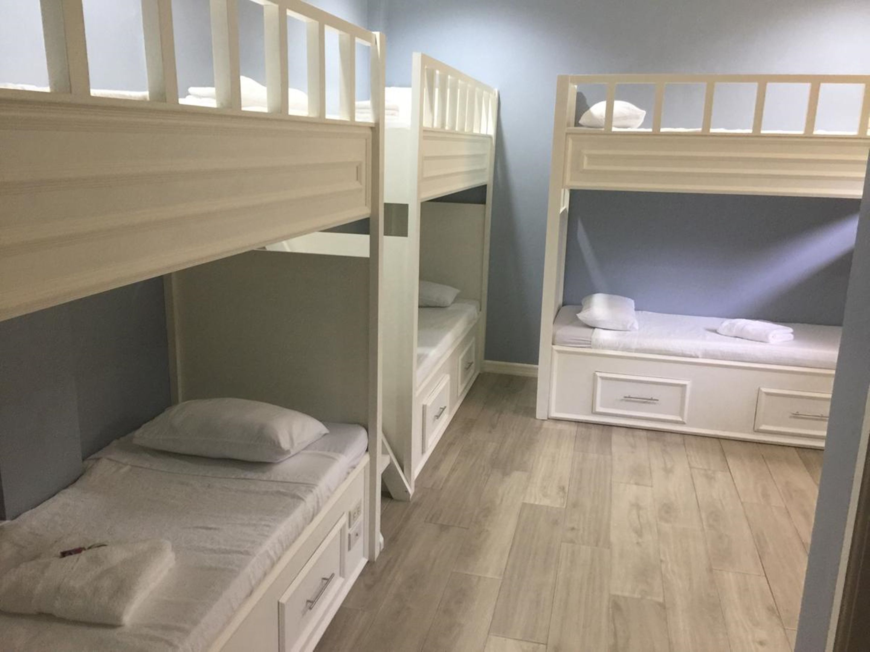 A room with bunk beds, a small desk, and a drawer unit.