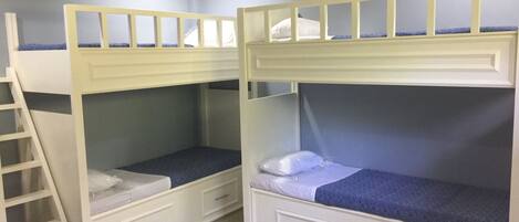 Una habitación con literas, una escalera y cajones empotrados.