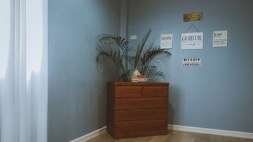 Habitación de esquina con cómoda de madera, planta en maceta y decoración de pared inspiradora.