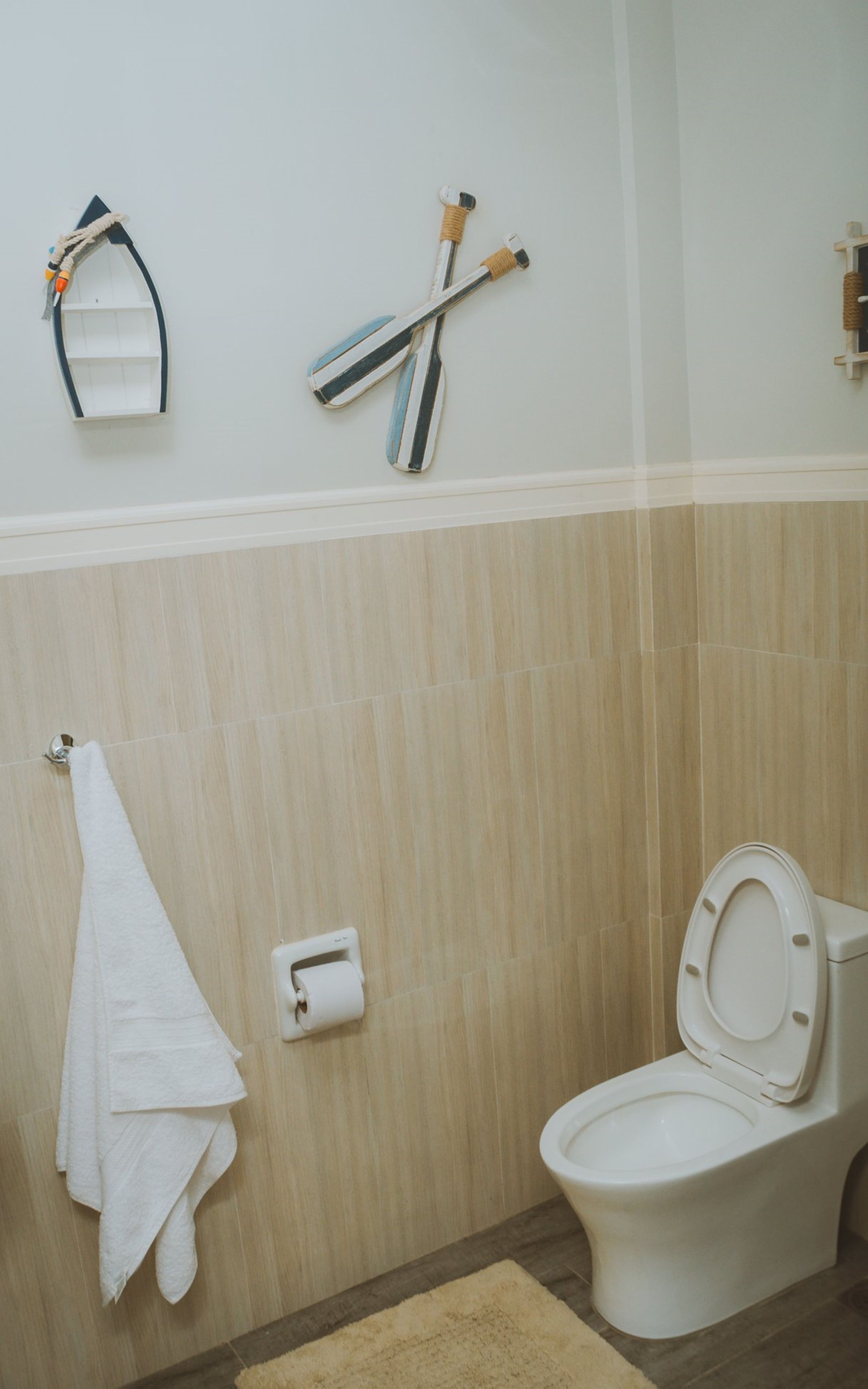 A bathroom with a toilet, a towel rack, and a toilet paper holder.