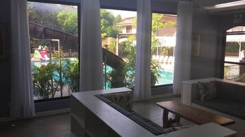 Una habitación moderna con un ventanal grande con vistas a una zona de piscina, un sofá y una mesita.