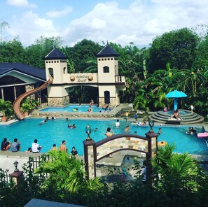 Een resort met een groot zwembad, een glijbaan en een bord waarop 'Bella Vista Resort' staat.