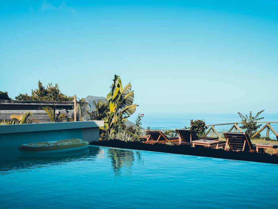 Una piscina al aire libre, sombrillas, sillones reclinables de piscina