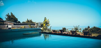 Una piscina al aire libre, sombrillas, sillones reclinables de piscina