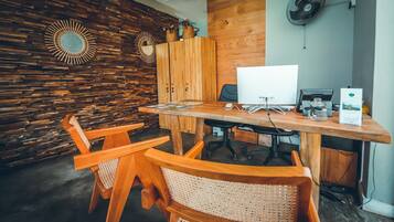 A wooden desk with a computer, two chairs, and a wall with a wooden panel and a mirror.