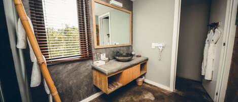 A bathroom with a wooden vanity, a large mirror, and a towel rack.