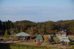 A lodge with multiple buildings, including a main house with a balcony and several smaller cabins, set in a forested area with a clear sky. - Wariyama Shinrin Koen Tenkomori (Toyama)