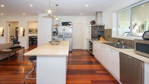 Una cocina moderna con una isla central, electrodomésticos de acero inoxidable y un amplio ventanal que proporciona luz natural.