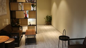 Ein modernes Wohnzimmer mit einer Couch, einem Holztisch, einem Bücherregal und einem Topfpflanzen.