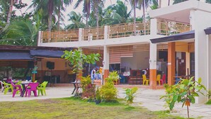 A two-story building with a covered outdoor seating area, multiple doors, and a balcony. - Gana Siargao Island Resort (General Luna)