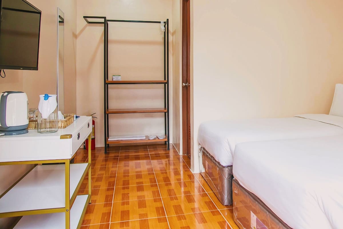 Una habitación de hotel con cama, escritorio con hervidor, estante y armario.