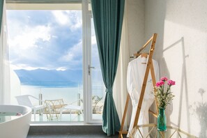 A room with a view of the sea, a white bathtub, a painting easel, and a vase with flowers. - Butterfy Seaview Resort Villa (Dali)