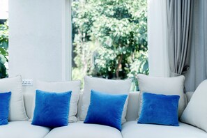 A white sofa with blue cushions in a room with a window and a power outlet. - Butterfy Seaview Resort Villa (Dali)