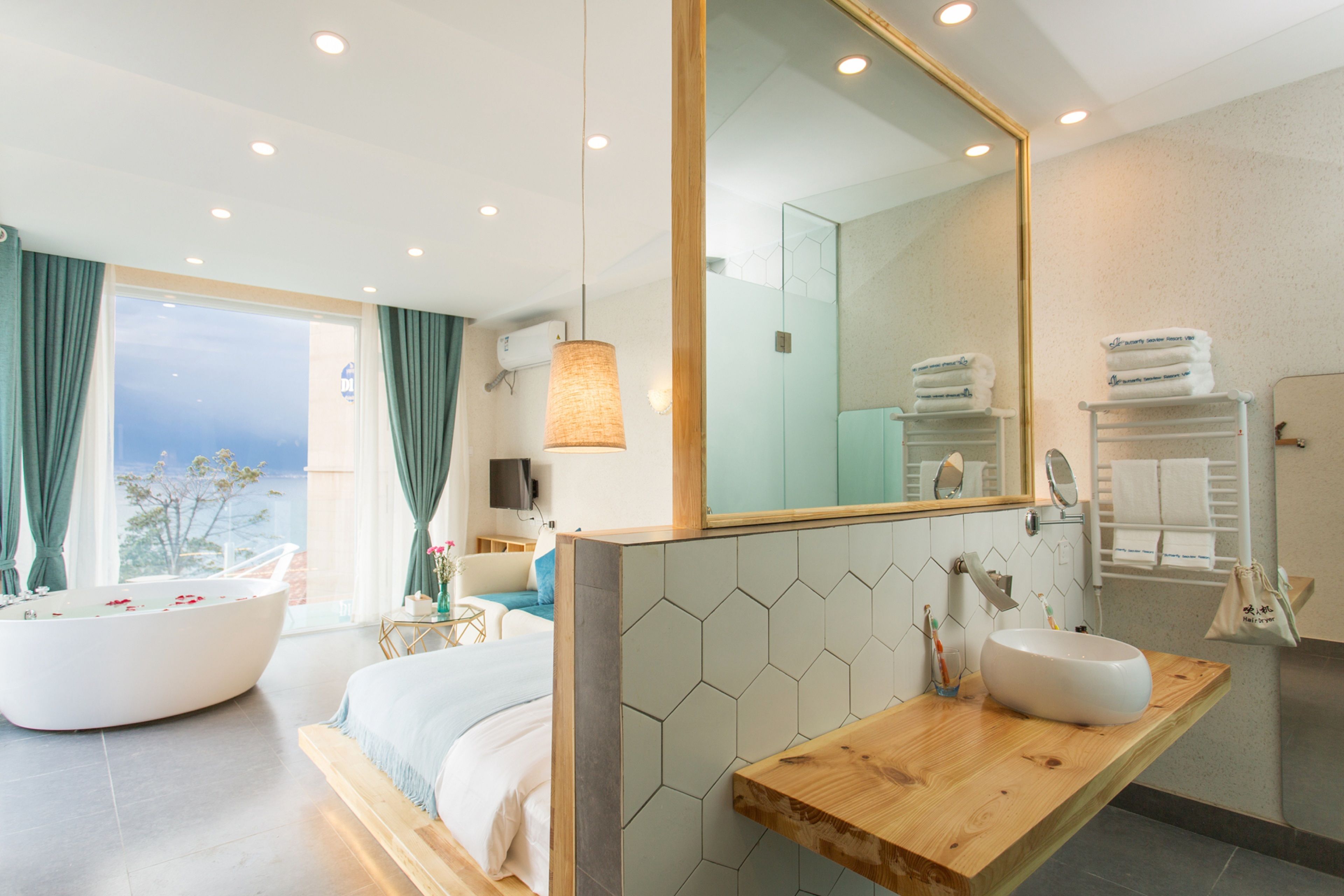 A modern bathroom with a large mirror, a wooden vanity, a bathtub, and a shower area.