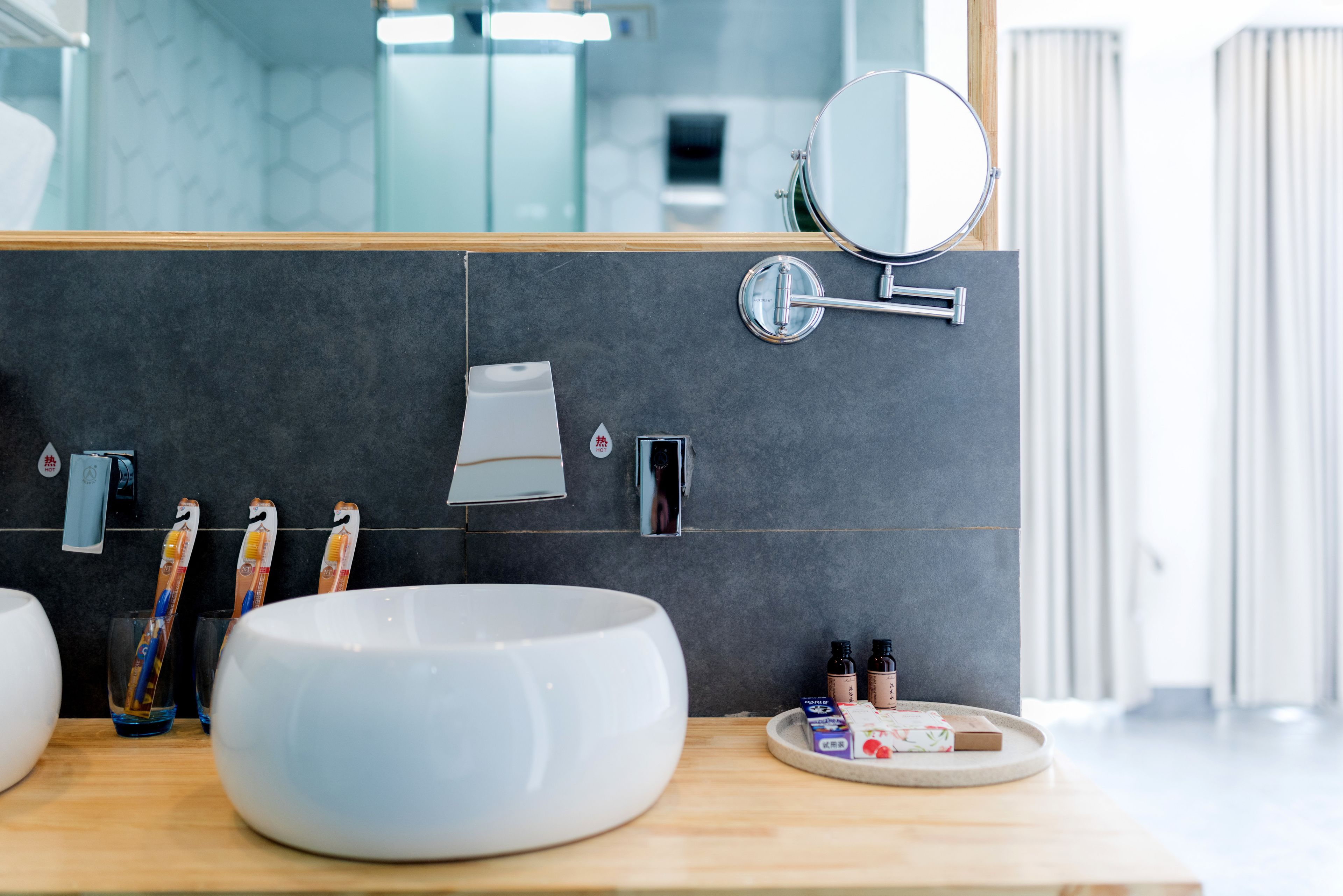A modern bathroom with a large white basin, a mirror, and a towel rack.
