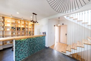 A modern interior with a wooden reception desk, shelves with decorative items, a green patterned wall, and a staircase with wooden steps. - Butterfy Seaview Resort Villa (Dali)